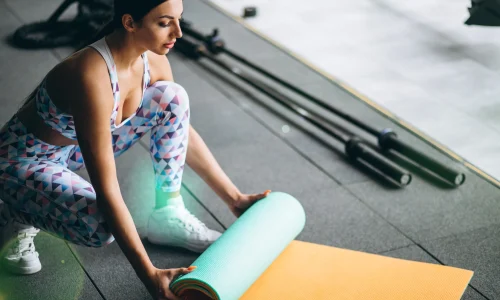 woman-exercing-gym-holding-yoga-mat